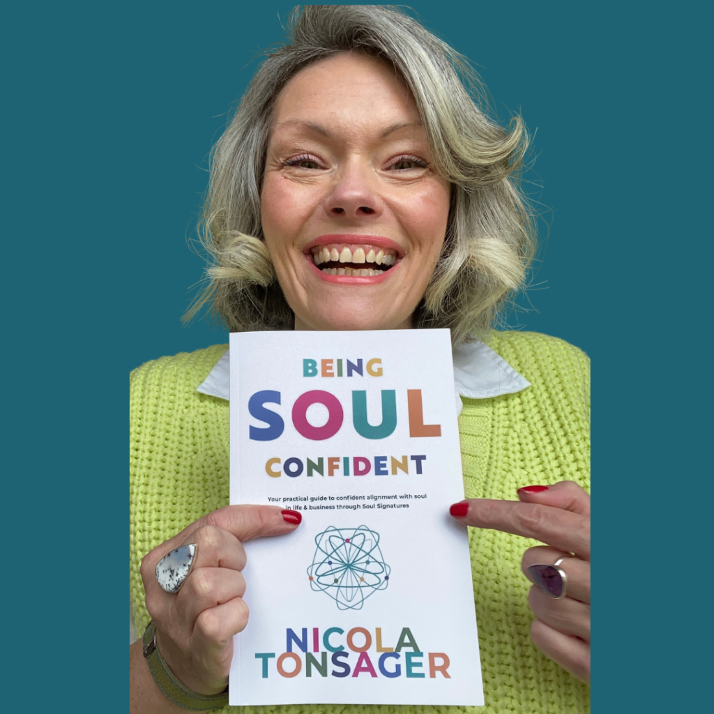Nicola Tonsager smiling with No 1 best selling book Being Soul Confident
